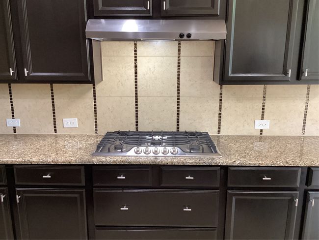 Kitchen with cooktop, extractor fan, tasteful backsplash, and dark cabinetry | Image 9