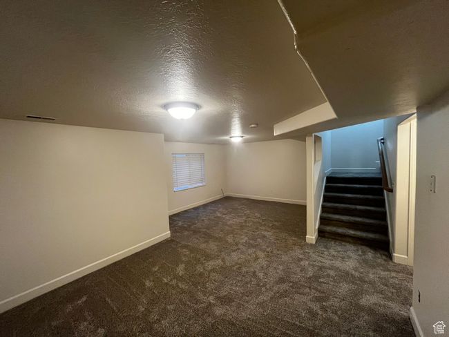 Finished basement featuring carpet flooring, stairs, and a textured ceiling | Image 14
