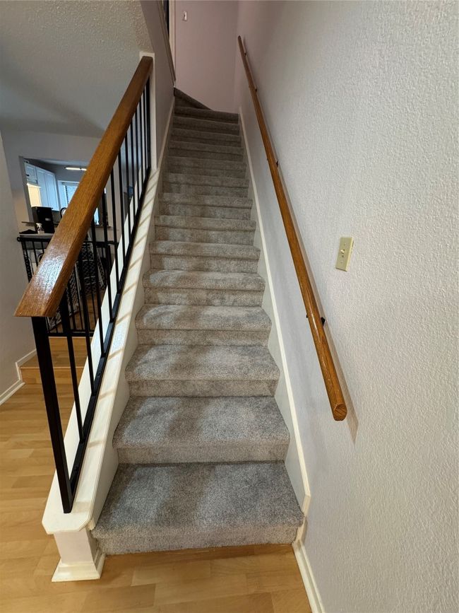 Stairway featuring a textured wall and wood finished floors | Image 11