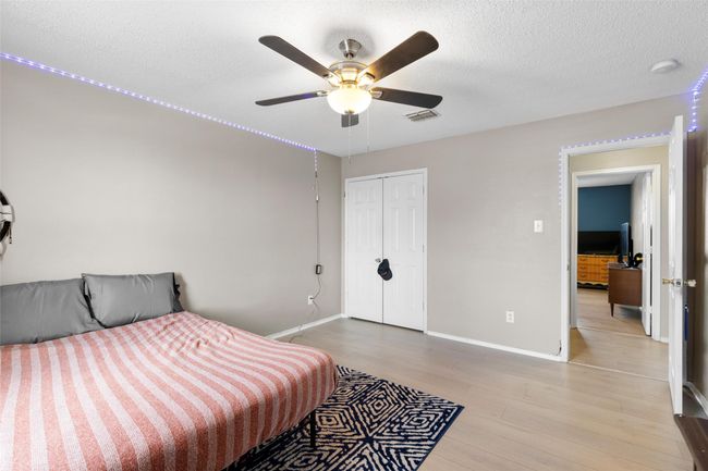 Bedroom with light wood finished floors, a closet, a ceiling fan, and a textured ceiling | Image 25
