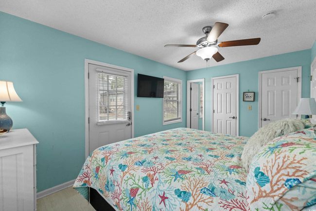 Bedroom with a textured ceiling, baseboards, wood finished floors, and ceiling fan | Image 15