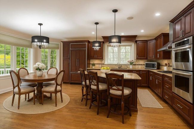 Kitchen featuring stainless steel appliances, a sink, light wood-style flooring, wall chimney exhaust hood, and recessed lighting | Image 8