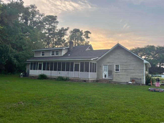 Back of property at dusk featuring a sunroom, a chimney, a yard, and entry steps | Image 36