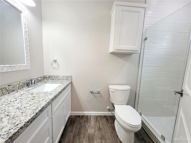 Full bathroom featuring vanity, toilet, wood finished floors, a stall shower, and baseboards | Image 8