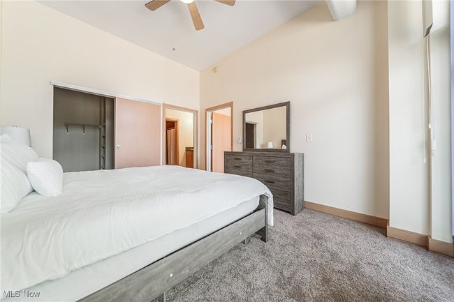 Carpeted bedroom with ceiling fan, balcony access, walk-in closet, and full bathroom. | Image 19