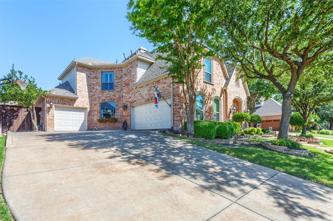 Traditional home featuring brick siding, driveway, an attached garage, and a shingled roof | Image 36