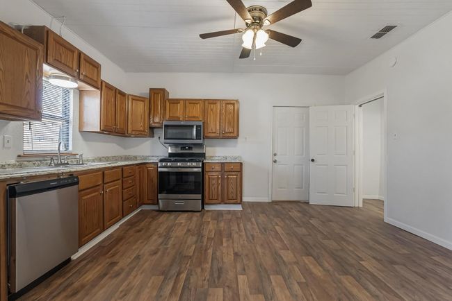 Kitchen with dark hardwood / wood-style flooring, sink, ceiling fan, and appliances with stainless steel finishes | Image 12