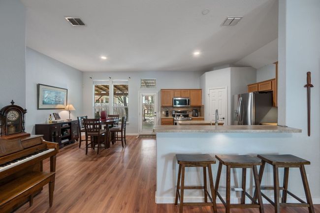Kitchen with appliances with stainless steel finishes, a kitchen bar, wood finished floors, decorative backsplash, and recessed lighting | Image 7