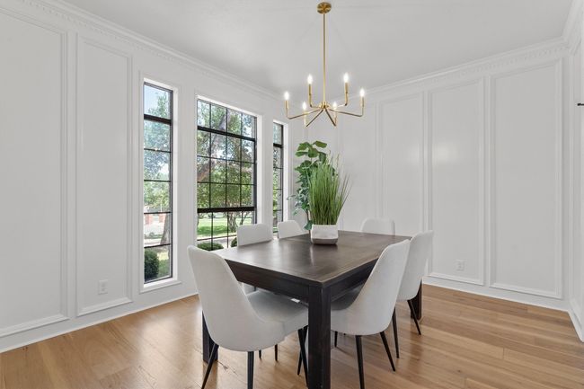 Dining space featuring a decorative wall, a chandelier, light wood-style flooring, and crown molding | Image 12