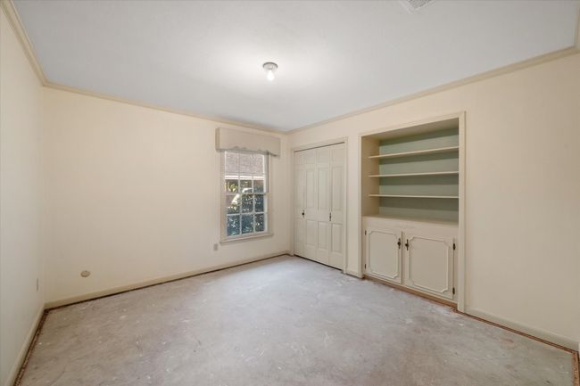 Center bedroom with concrete flooring and ornamental molding. Features built in book shelves | Image 27