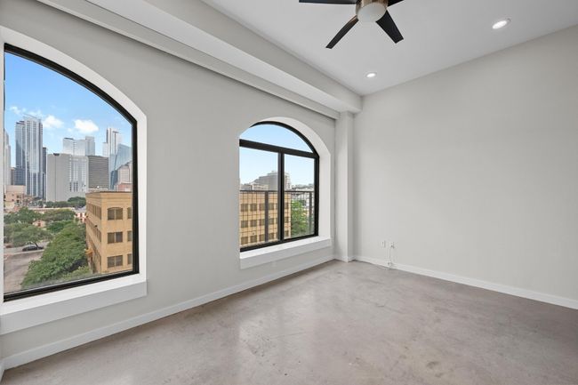 Empty room with a ceiling fan, a view of city, concrete flooring, and recessed lighting | Image 11