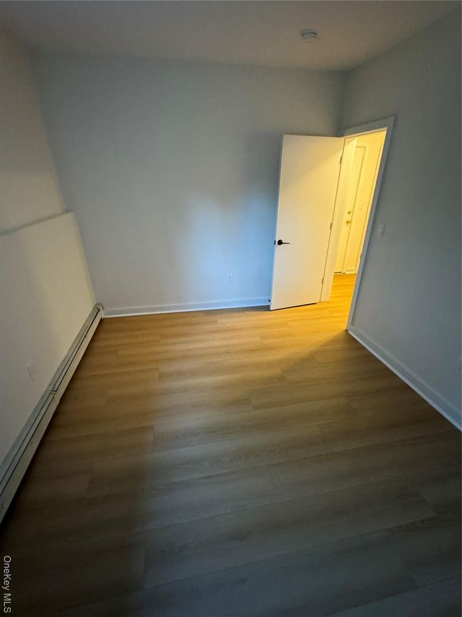 Spare room with a baseboard heating unit and wood finished floors | Image 6
