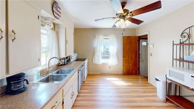 Kitchen featuring white cabinets, light hardwood / wood-style floors, ceiling fan, and a wealth of natural light | Image 2