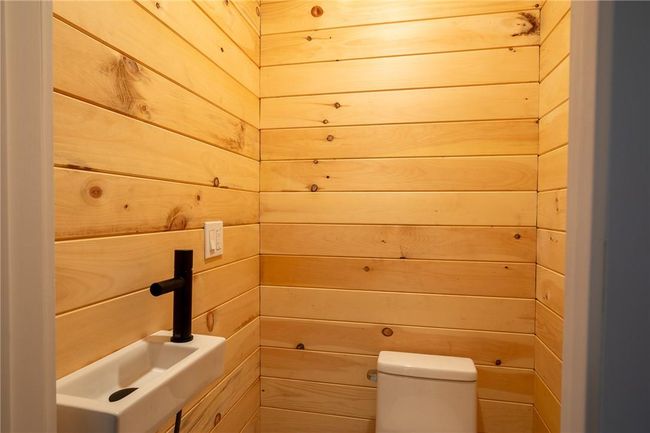 Bathroom with toilet, wooden walls, and sink | Image 13
