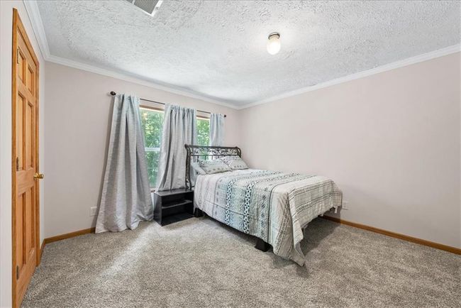 Bedroom featuring carpet, baseboards, a textured ceiling, and crown molding | Image 18
