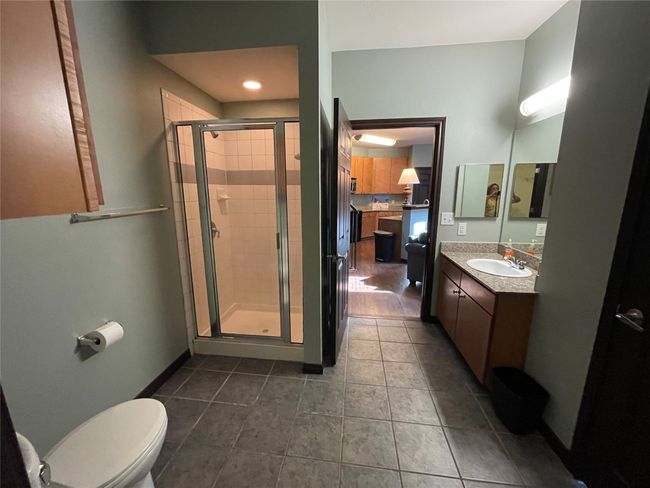 Full bath featuring vanity, a shower stall, toilet, tile patterned flooring, and baseboards | Image 18
