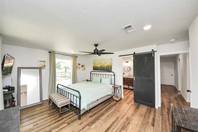 Cozy and stylish primary bedroom featuring a sliding barn door that opens to an updated, private en-suite bath. | Image 16