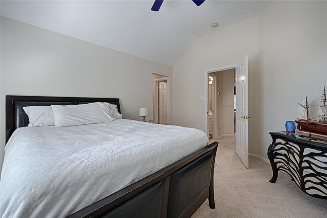 Bedroom featuring light carpet, lofted ceiling, a ceiling fan, and baseboards | Image 9