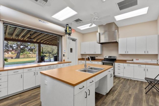 Kitchen with white cabinetry, dark wood-style floors, a center island with sink, and light countertops | Image 27