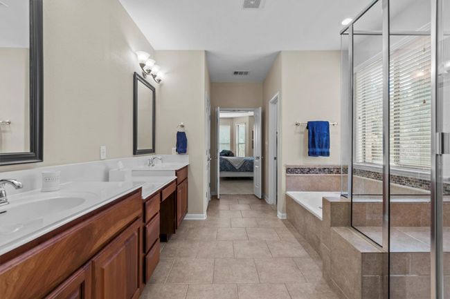 A luxurious soaking tub and glass-enclosed shower are accented with designer tilework and flooded with natural light. | Image 20