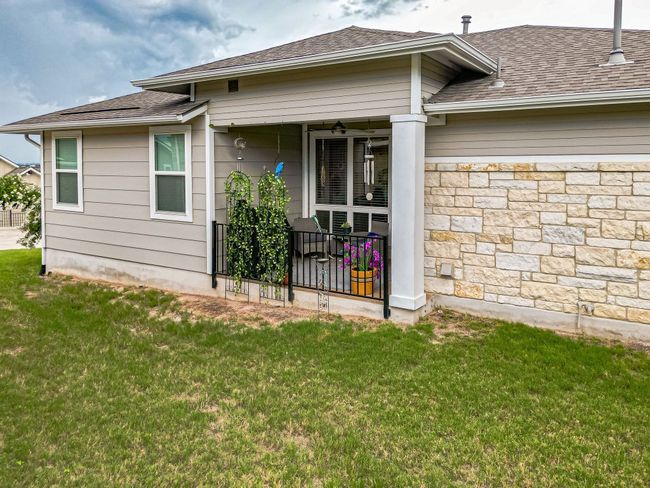 Rear view of house with a lawn, a shingled roof, covered porch, and stone siding | Image 24