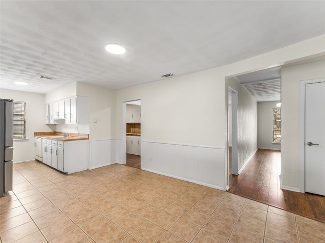 Kitchen with white cabinetry, light tile patterned floors, plenty of natural light, and stainless steel refrigerator | Image 16