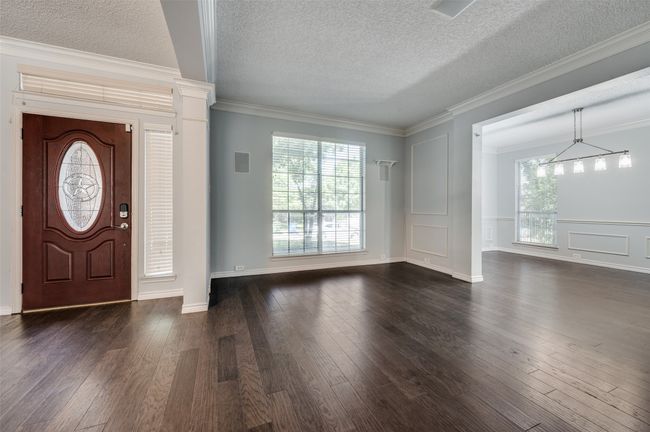Entrance foyer with a notable chandelier, a textured ceiling, crown molding, and dark wood-style flooring | Image 4