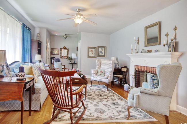 Living area featuring ceiling fan, wood finished floors, a fireplace, and baseboards | Image 13