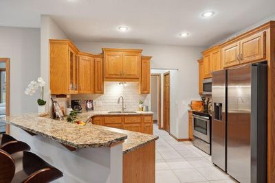 Can you imagine yourself making family meals here? Maple cabinetry, a nice backsplash and ceramic tile. | Image 3