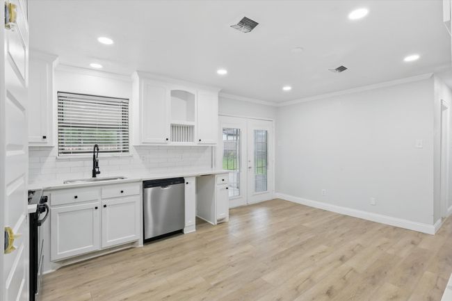 Kitchen featuring stainless steel appliances, a sink, crown molding, light countertops, and healthy amount of natural light | Image 11