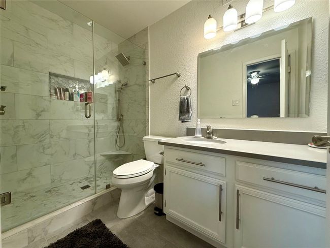 Bathroom featuring toilet, a textured wall, a shower stall, and vanity | Image 12