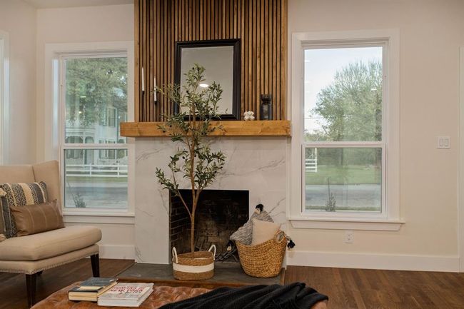 The cozy wood-burning fireplace is complete with an elegant tile surround complimented by a wood mantel with vertical detailing ascending towards the ceiling. | Image 6
