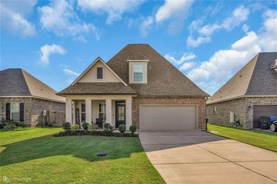 View of front of property with covered porch, a garage, and a front lawn | Image 1