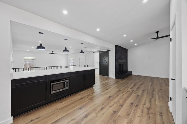 Kitchen featuring dark cabinets, a ceiling fan, open floor plan, a barn door, and stainless steel microwave | Image 10