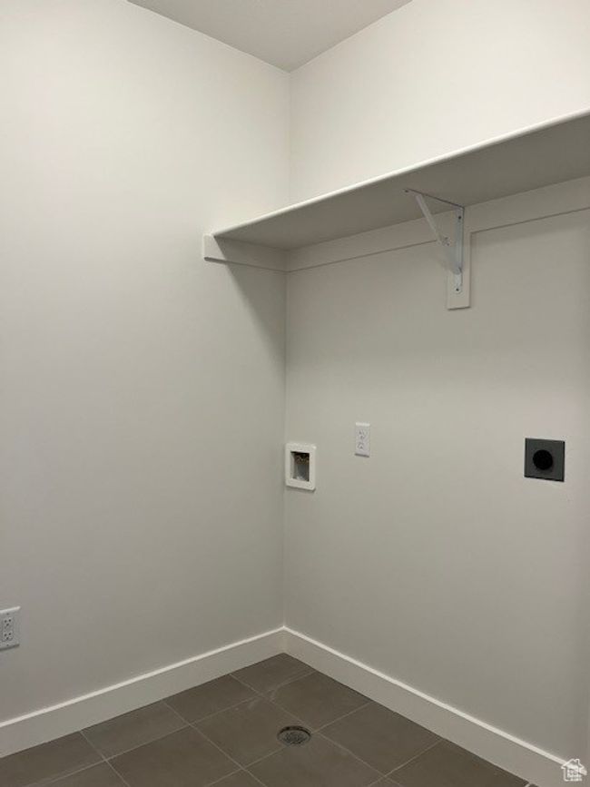 Clothes washing area featuring electric dryer hookup, laundry area, washer hookup, dark tile patterned flooring, and baseboards | Image 9
