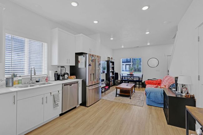 Kitchen with appliances with stainless steel finishes, a sink, light wood-style floors, light countertops, and white cabinets | Image 7