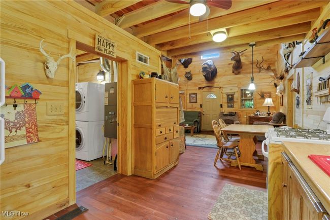 Kitchen featuring wooden walls, range with gas stovetop, dark wood finished floors, open floor plan, and ceiling fan | Image 14