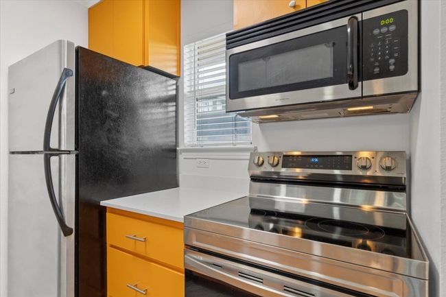 Kitchen with stainless steel appliances and light countertops | Image 9