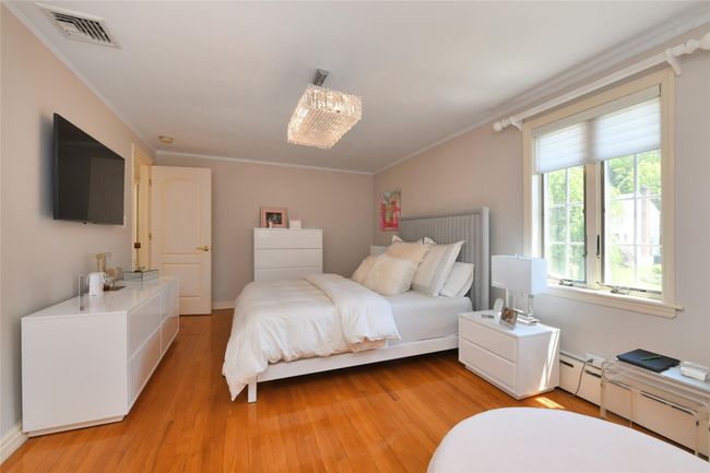Bedroom with ornamental molding, light wood-style flooring, and visible vents | Image 15