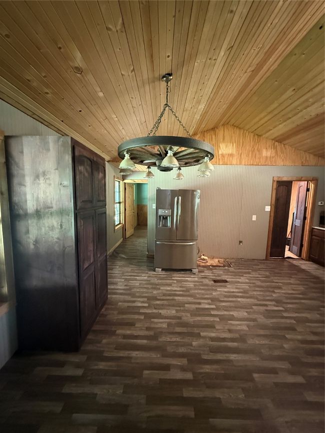 Hallway with dark wood-type flooring, lofted ceiling, wooden walls, and wood ceiling | Image 22
