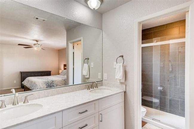 Ensuite bathroom with double vanity, toilet, a stall shower, and ceiling fan | Image 15