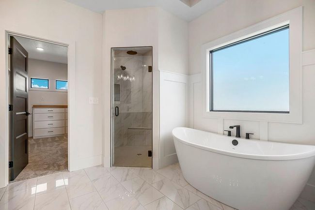 Full bathroom featuring a stall shower, marble look tile flooring, and a freestanding tub | Image 21