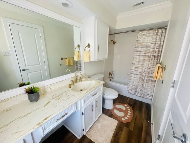Bathroom featuring wood finished floors, vanity, toilet, ornamental molding, and shower / bath combo with shower curtain | Image 16