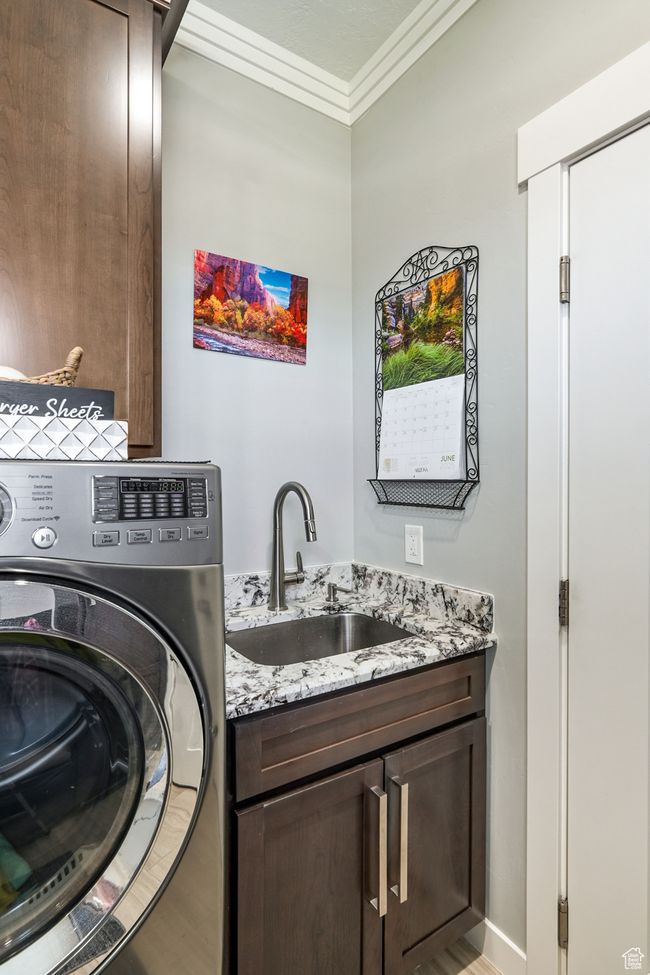 Washroom featuring washer / dryer, cabinet space, crown molding, and light wood-style floors | Image 36