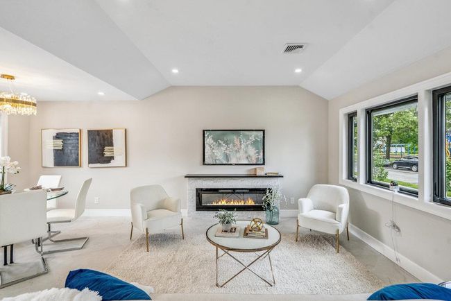 Living area featuring lofted ceiling, a glass covered fireplace, recessed lighting, and a chandelier | Image 17