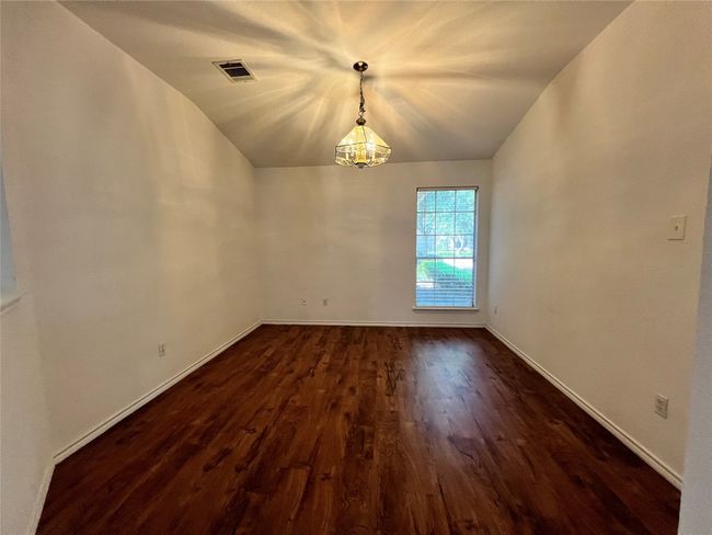 Empty room featuring lofted ceiling, dark wood-type flooring, baseboards, and a chandelier | Image 4