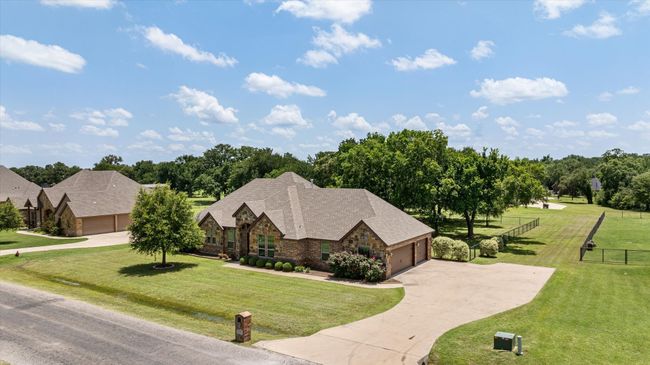 View of front of property featuring stone siding, driveway, an attached garage, and a shingled roof | Image 36
