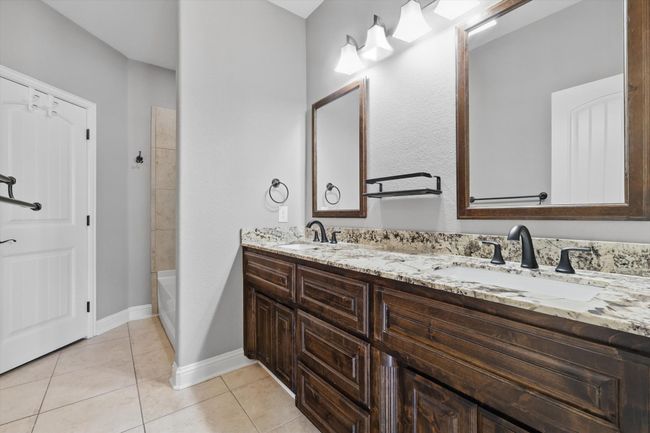 Full bathroom with double vanity, tile patterned flooring, baseboards, and tub / shower combination | Image 19
