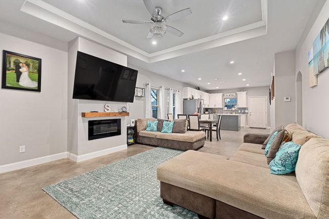 Living room with a raised ceiling, ornamental molding, and ceiling fan | Image 5
