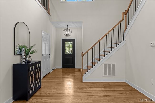 Foyer entrance with a high ceiling, wood finished floors, a chandelier, and stairway | Image 9